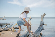 A Little Girl Clambering , Balancing And Walking On A Tree Trunk At The Beach.