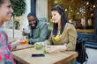 © KOTO - Smiling young friends drinking juice at sidewalk cafe