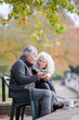 © KOTO - Active senior couple talking, enjoying coffee at autumn park cafe