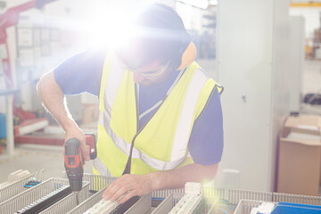 Wall Mural - Male engineer with power drill assembling equipment in steel factory