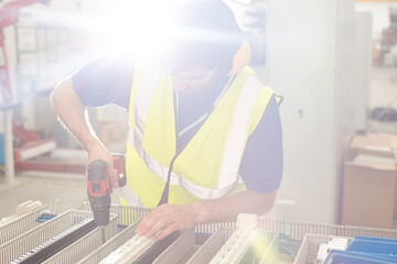 Wall Mural - Male engineer with power drill assembling equipment in steel factory