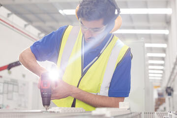 Wall Mural - Male engineer with power drill assembling equipment in steel factory