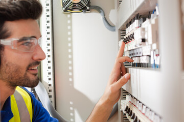 Male worker wearing ear protectors, operating machinery at control panel in factory