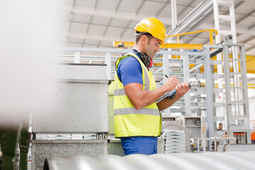 Poster - Factory worker with clipboard inspecting steel parts in factory