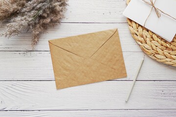 Brown kraft paper envelope mockup for stationery design presentation, boho style background with pampas grass, wicker straw mat, flat lay.