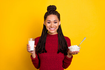 Photo of sweet charming dark skin lady wear red pullover smiling holding cottagecheese milk glass isolated yellow color background