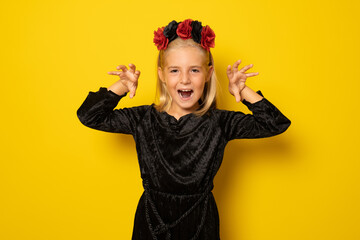 portrait of little girl in black clothing isolated over yellow background.