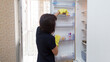 © ALEXEY - A woman washes the internal shelves of refrigerator in yellow rubber gloves, cleaning the apartment.