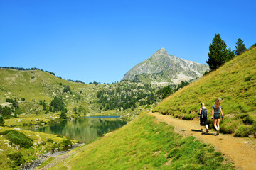 Poster - Hikers on a trip in Neouvielle national nature reserve, Lac du Milieu, French Pyrenees. Beautiful summer mountain landscape in the sunny day.