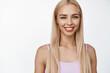 © Cookie Studio - Beauty and skin care. Smiling blond girl with natural makeup, looking happy at camera, standing in tank-top against white background