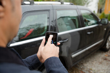 Wall Mural - Man setting car alarm from smart phone in driveway