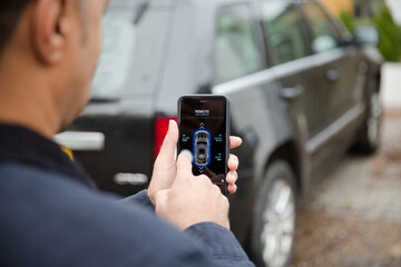 Wall Mural - Man setting car alarm from smart phone in driveway