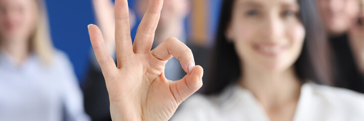 Wall Mural - Business woman showing ok gesture on background of colleagues closeup