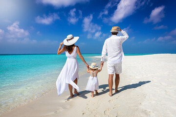 A elegant family in white summer clothing walks hand in hand down a tropical paradise beach and enjoys their holidays