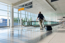 Tourist With Baggage Walking On  Moving Walkway In  Airport, Subject Out Of Focus