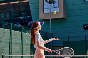 Wall Mural - portrait of sporty lady tennis player with racket, raising throwing ball up. confident slim fit female tennis player in uniform training exercising at summer day. sport, fitness, people concept