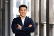 © Liubomir - portrait of a cheerful asian in a business suit looks at the camera with crossed arms and smiles