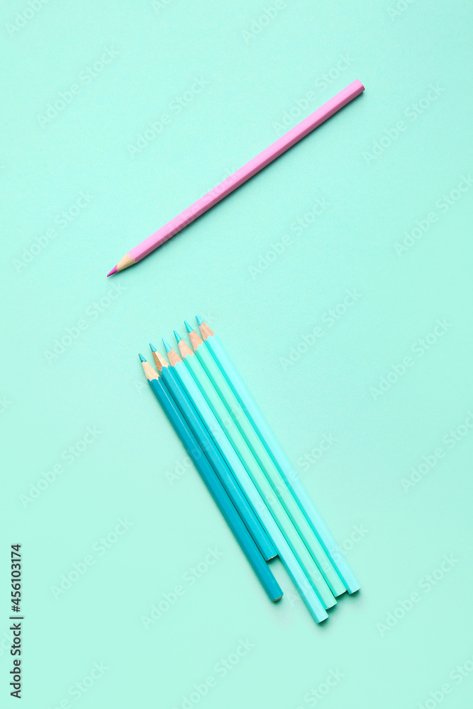 Pink pencil among blue ones on color background. Concept of uniqueness