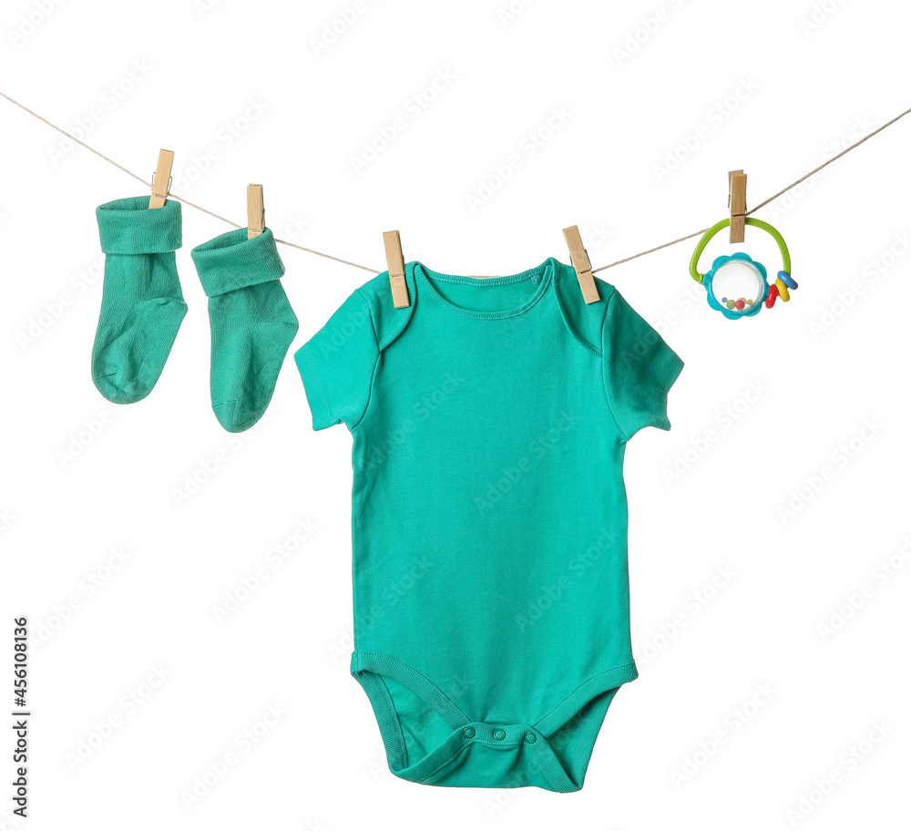 Baby clothes and toy hanging on rope against white background