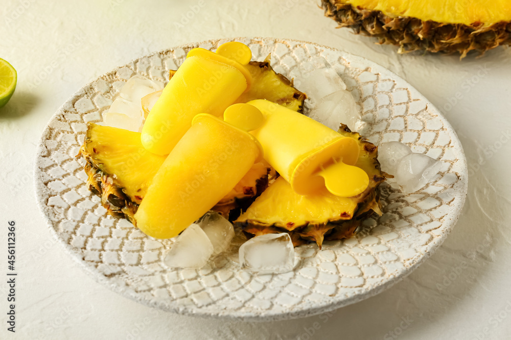Plate with tasty pineapple popsicles on light background