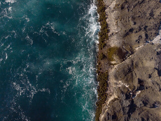 Seascape. Dark turquoise ocean water with light white waves and rocky coast. Beauty of nature. View from above. Drone shooting. Ecology, tourism, recreation, the greatness of nature.