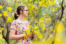 Smiling Female In Yellow Dress With Wattle Blossom Bouquet In Native Bushland