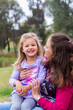 © Austockphoto - Happy mother and daughter laughing and giggling together outside at park