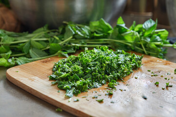 Canvas Print - Chef cuts basil according to the recipe for cooking on wooden board in the kitchen