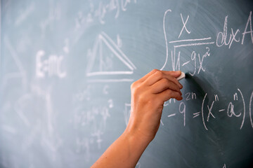 teacher or student writing on blackboard during math lesson in school classroom