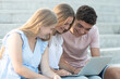© Egoitz - Happy teenagers sitting on stairs working together on a laptop. Teamwork in adolescence concept.