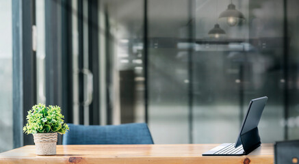 Mockup tablet with magic keyboard on wooden table in dark tone office room.