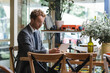 © LIGHTFIELD STUDIOS - curly businessman in formal wear and glasses using laptop in cafe