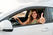 © Alvaro - Pretty young woman driving a car and showing thumbs up out the window.