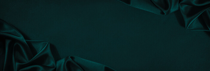dark blue green silk satin background. beautiful soft folds on the smooth surface of the fabric. lux