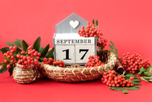 Calendar For September 17 : The Name Of The Month In English, Cubes With The Number 17 On A Decorative Tray, Branches Of Red Mountain Ash Around On A Crimson Background, Side View
