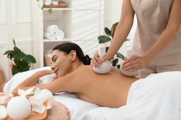 Wall Mural - Young woman receiving herbal bag massage in spa salon