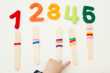 Wall Mural - Logic and counting game for early education. Stuffed felt numbers and Popsicle Sticks with hair tie gum on it. Each popsicle have dedicated number of ring.