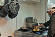 Crop ethnic chef preparing pappardelle on gas stove in kitchen