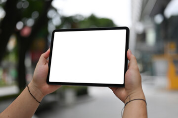 Poster - Cropped image of the hand using a white blank screen digital tablet in the park.