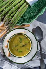 Wall Mural - Bowl with creme soup made from fresh green asparagus vegetables close up