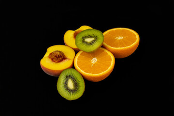 Poster - Closeup shot of fresh sliced orange, peach, and kiwi isolated on a dark background