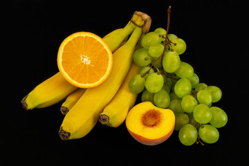 Sticker - Closeup of freshly sliced orange, peach, green grapes, and bananas isolated on a dark background