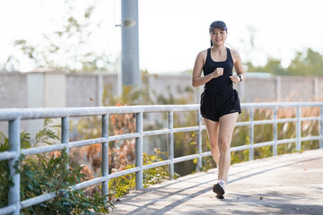 Poster - Healthy happy Asian runner in a black outfit jogging in a park during the sunset