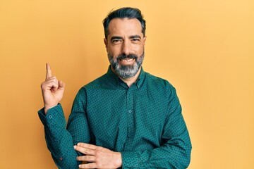 Sticker - Middle age man with beard and grey hair wearing business clothes with a big smile on face, pointing with hand and finger to the side looking at the camera.