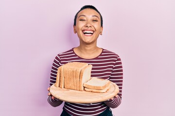 Poster - Beautiful hispanic woman with short hair holding sandwich bread smiling and laughing hard out loud because funny crazy joke.