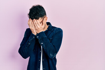 Young hispanic man wearing casual clothes and glasses with sad expression covering face with hands while crying. depression concept.