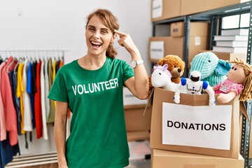 Sticker - Beautiful caucasian woman wearing volunteer t shirt at donations stand smiling pointing to head with one finger, great idea or thought, good memory