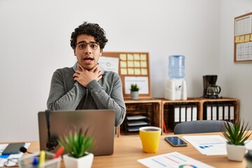 Canvas Print - Young hispanic man wearing business style sitting on desk at office shouting and suffocate because painful strangle. health problem. asphyxiate and suicide concept.