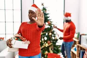 Sticker - Young african american couple standing by christmas tree doing stop gesture with hands palms, angry and frustration expression