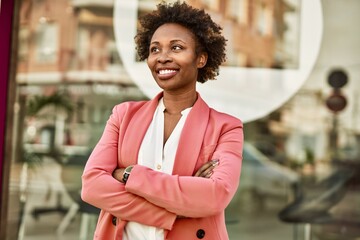 Beautiful business african american woman with afro hair smiling happy and confident outdoors at the city